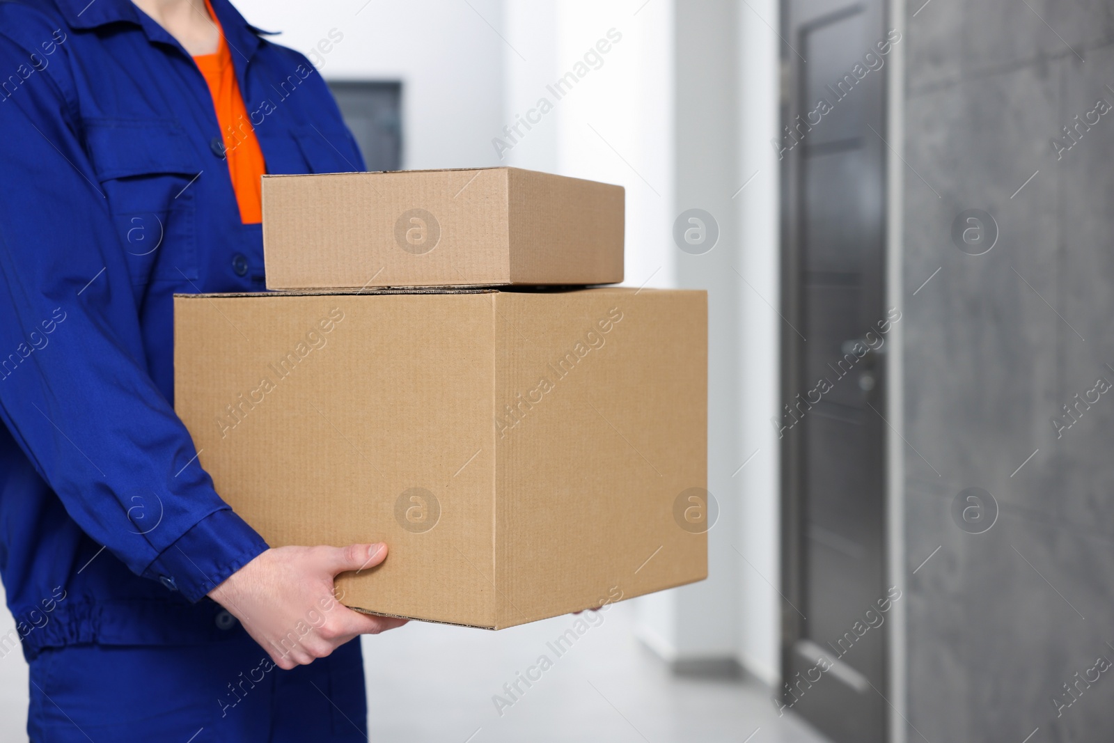 Photo of Courier with cardboard boxes in hallway, closeup