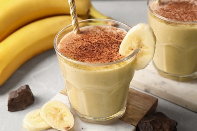 Photo of Tasty banana smoothie, fresh fruits and chocolate on white marble table, closeup