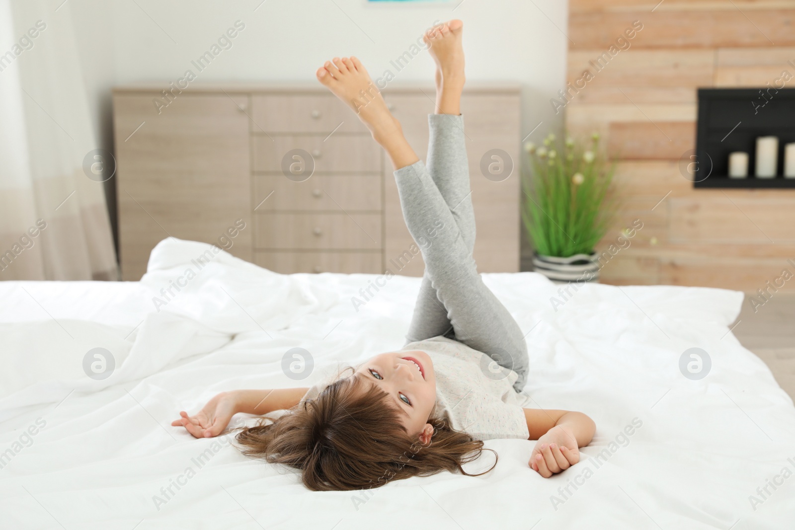 Photo of Cute little girl lying on bed at home