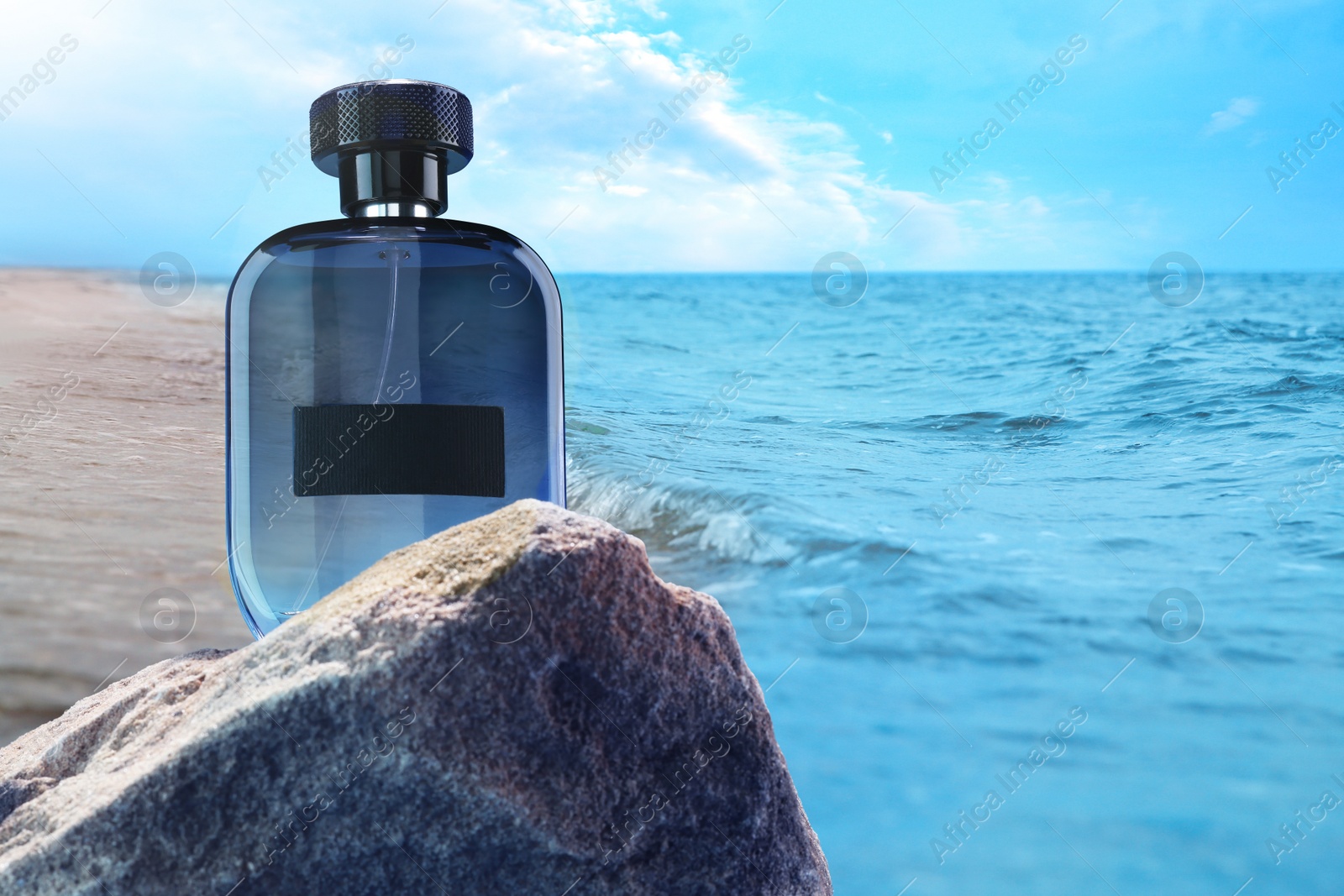 Image of Bottle of aquatic perfume on rock near ocean. Fresh sea breeze scent