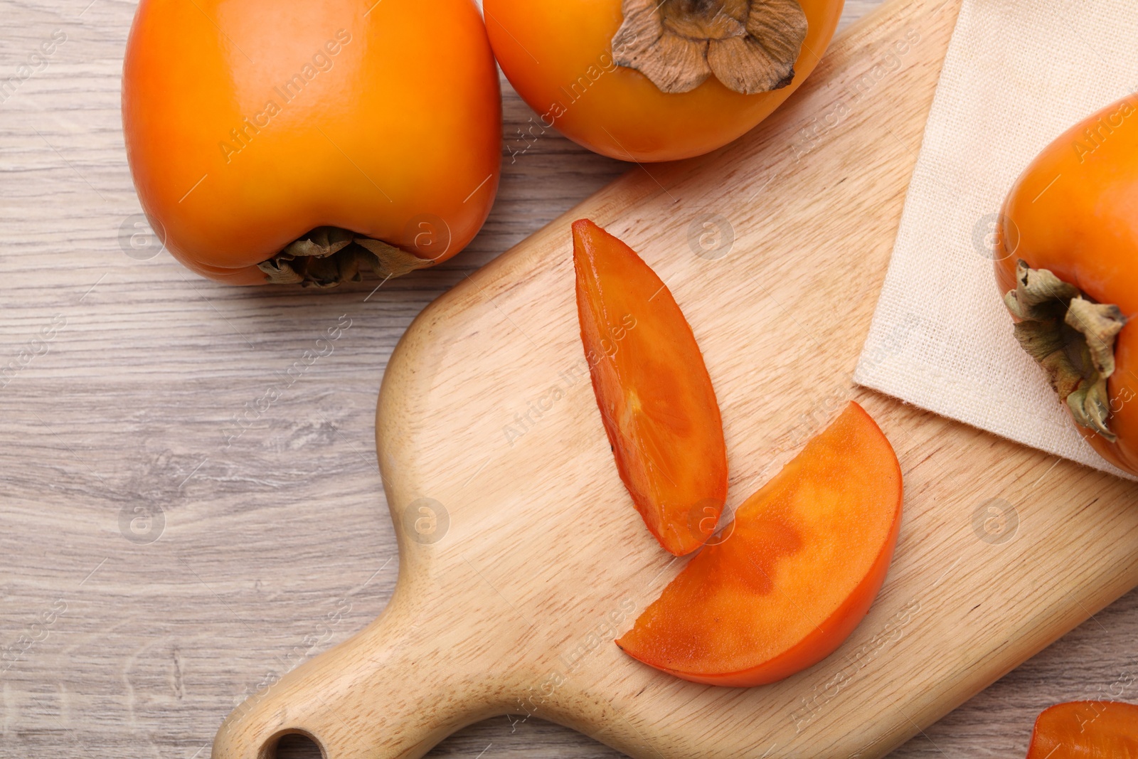 Photo of Delicious ripe persimmons on light wooden table, top view. Space for text