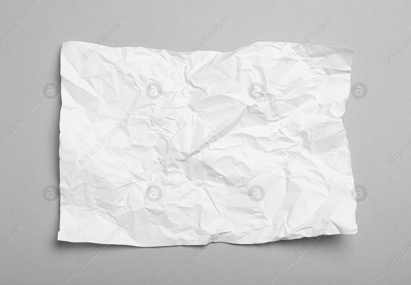 Photo of Sheet of white crumpled paper on grey background, top view