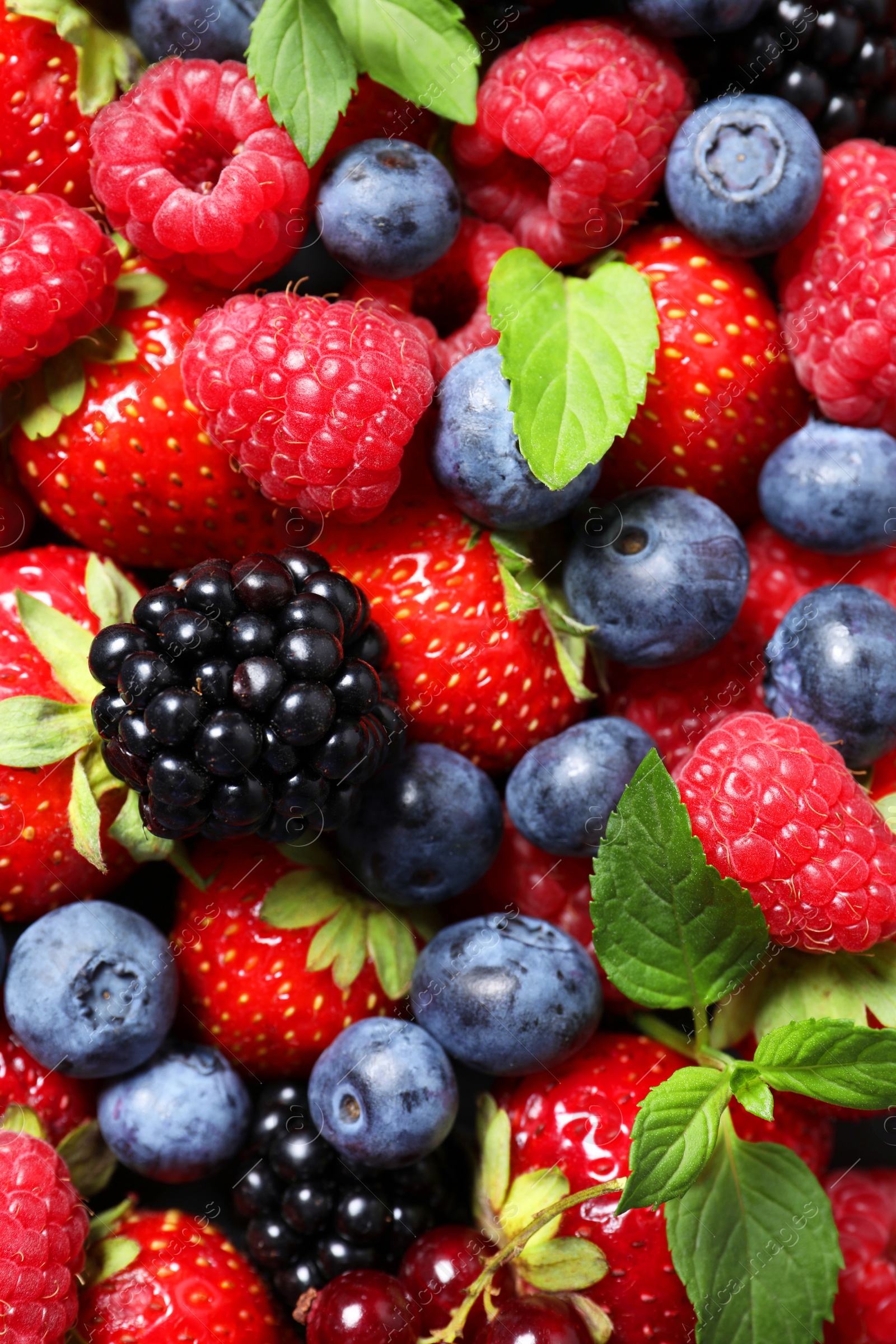 Photo of Assortment of fresh ripe berries with green leaves as background, top view