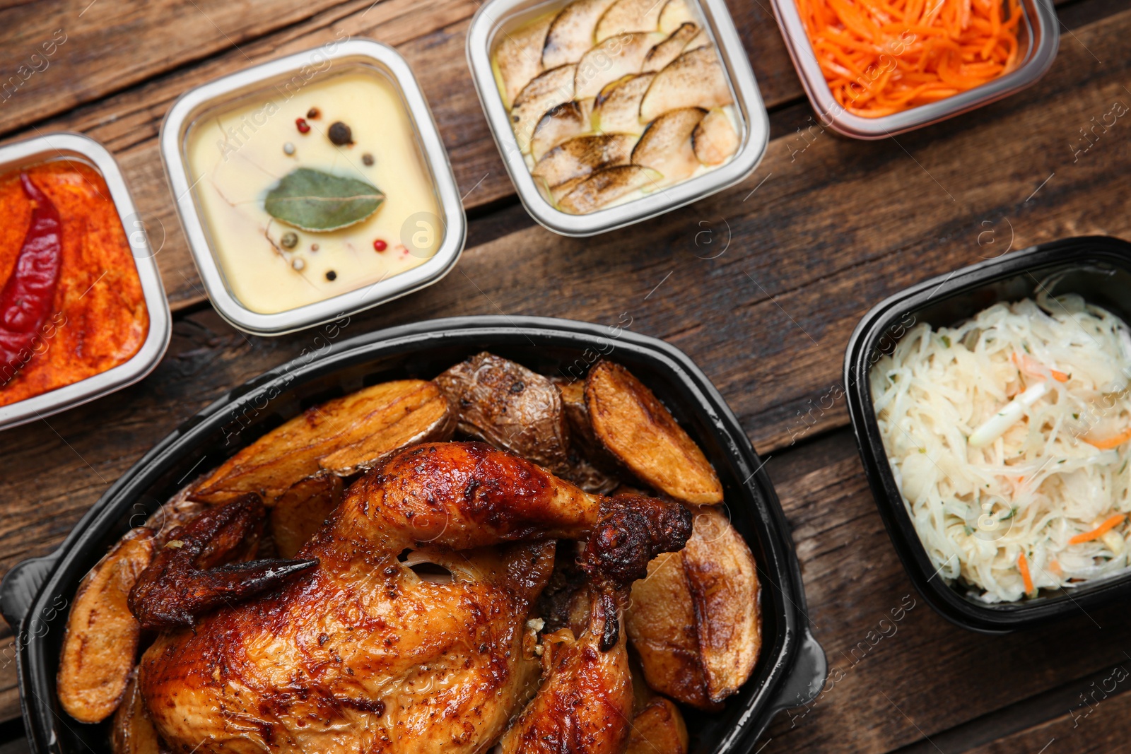 Photo of Plastic containers with different dishes on wooden table, flat lay. Food delivery service