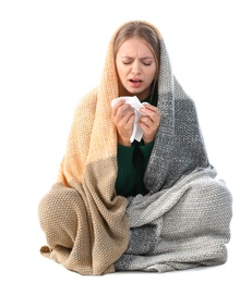 Young woman wrapped in warm blanket suffering from cold on white background