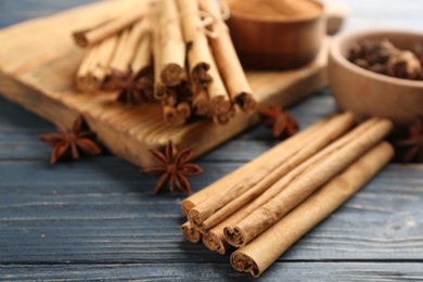 Photo of Aromatic cinnamon sticks and anise on blue wooden table