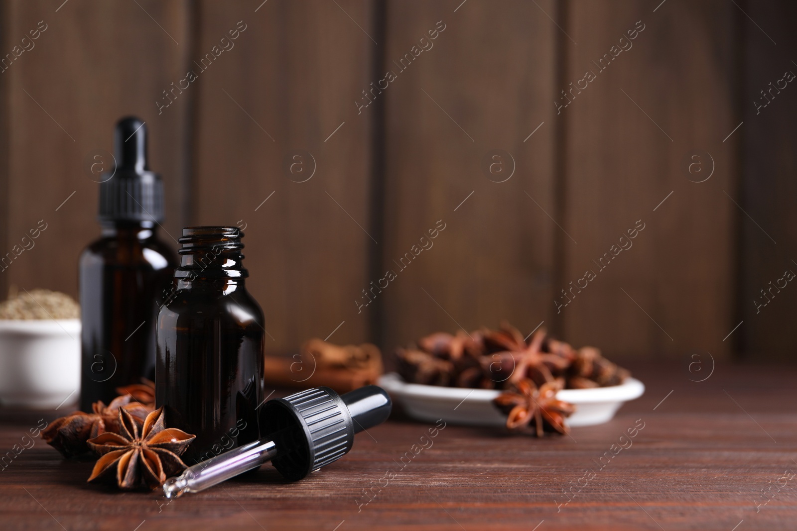 Photo of Anise essential oil and spice on wooden table, space for text