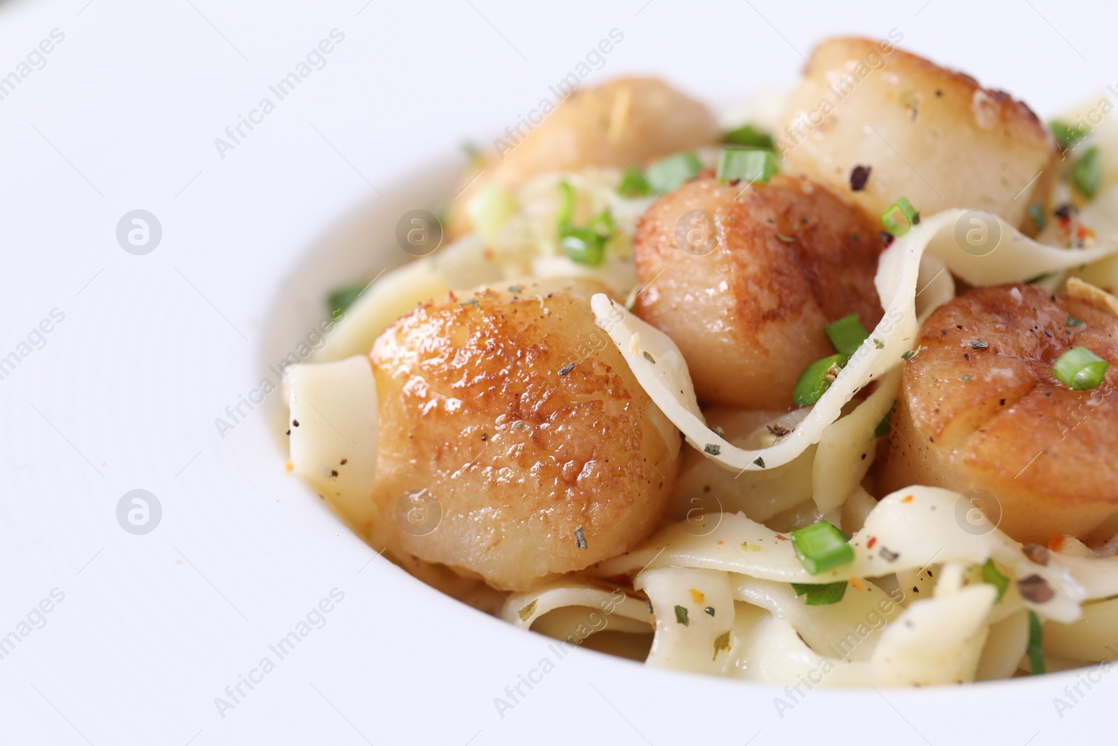 Photo of Delicious scallop pasta with spices in bowl, closeup