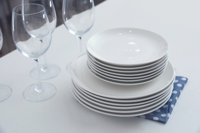 Stack of clean dishes and glasses on table in kitchen