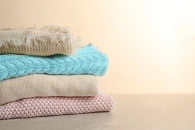 Photo of Stack of warm knitted clothes on table