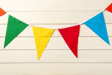 Bunting with colorful triangular flags on white wooden background. Festive decor