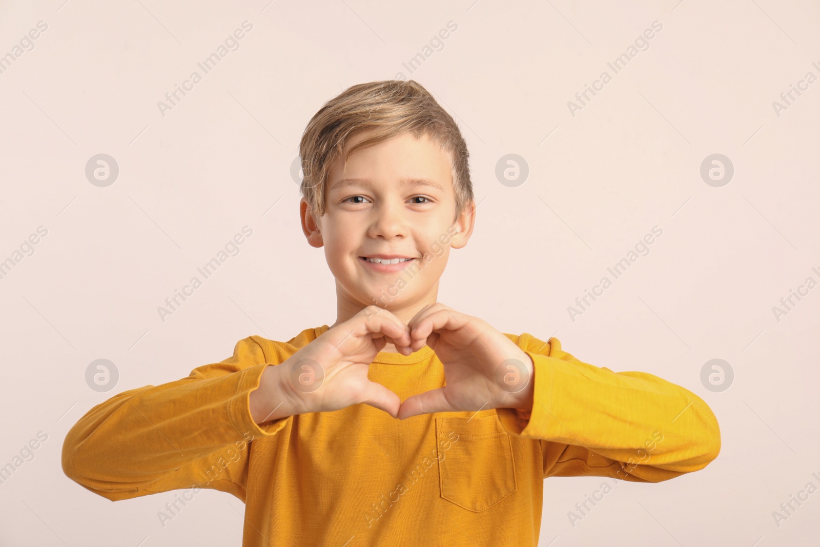 Photo of Cute boy making heart with his hands on white background