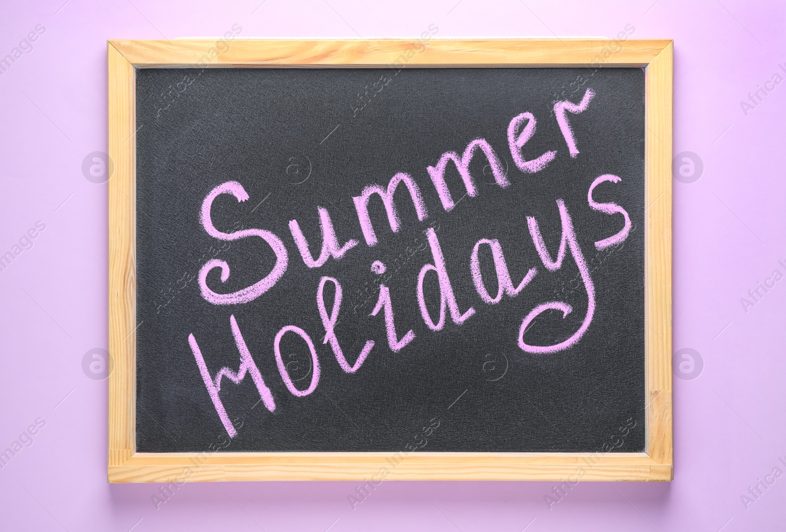 Photo of Chalkboard with phrase SUMMER HOLIDAYS on lilac background, top view. School's out