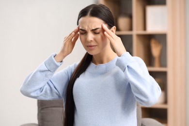 Pregnant young woman suffering from headache indoors