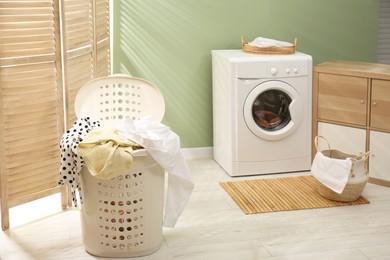 Laundry basket filled with clothes in bathroom. Space for text