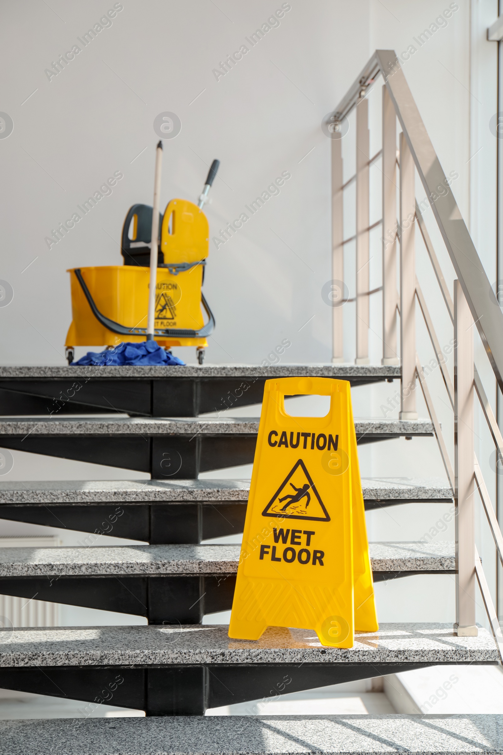 Photo of Safety sign with phrase Caution wet floor and mop bucket on stairs. Cleaning service