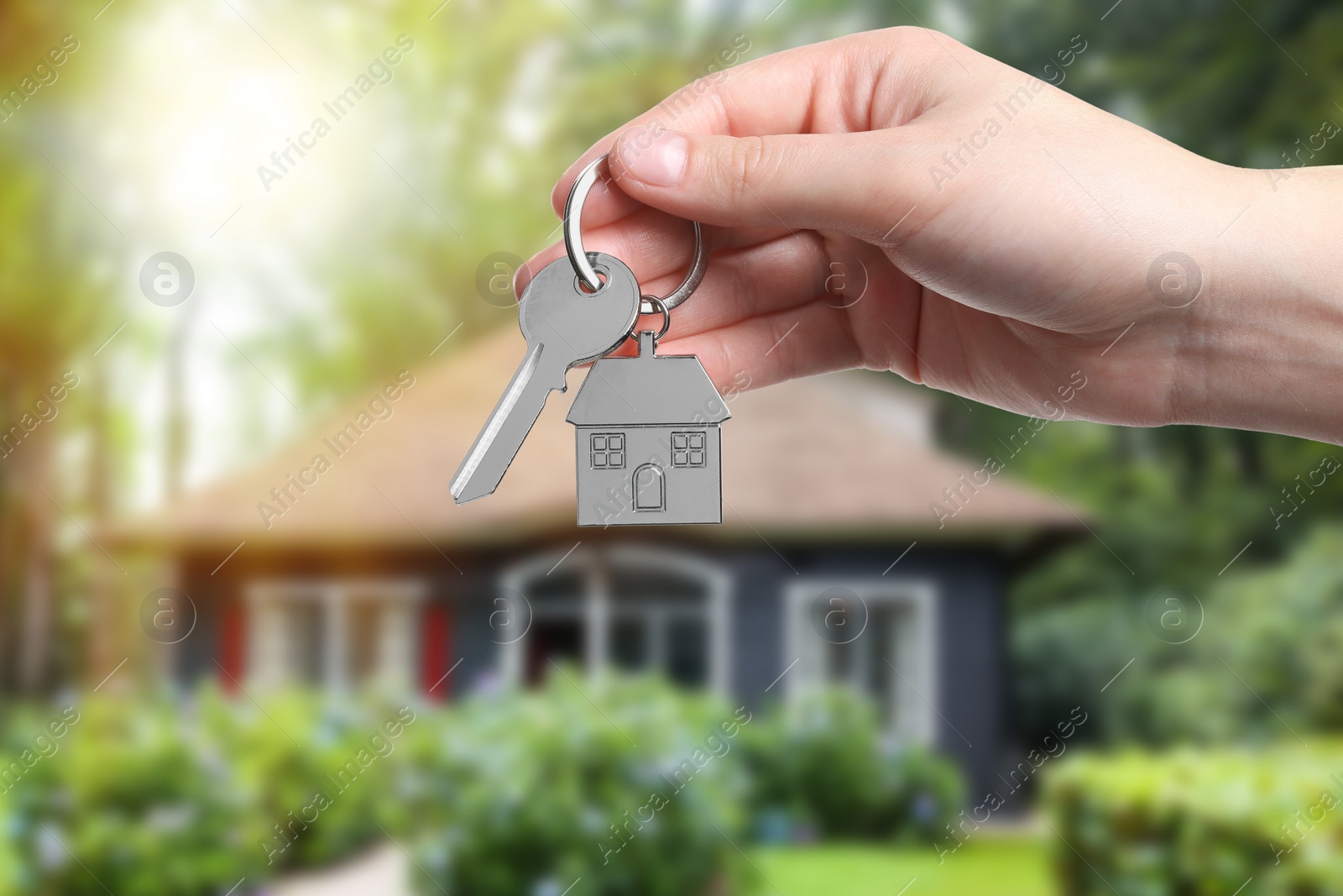 Image of Woman holding key near house outdoors, closeup