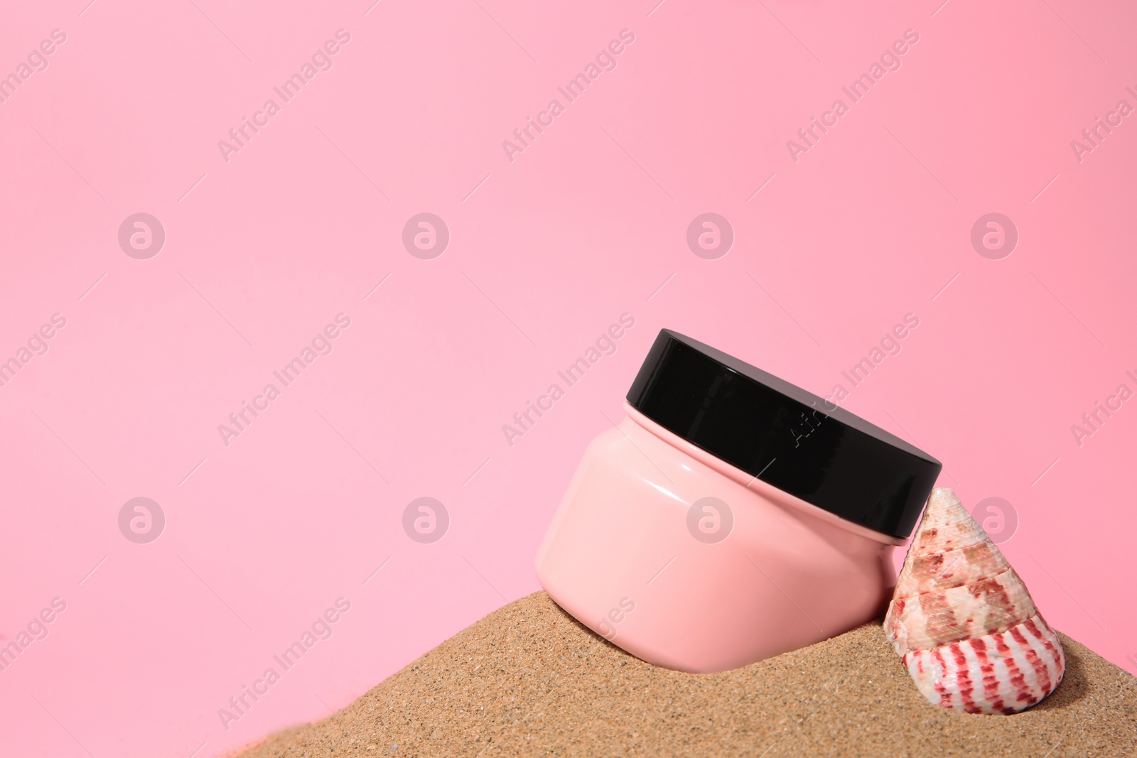 Photo of Jar of cream and seashell on sand against pink background. Space for text