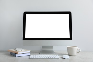 Photo of Modern computer with blank screen on light grey table. Mockup for design