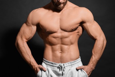 Photo of Muscular man showing abs on black background, closeup. Sexy body