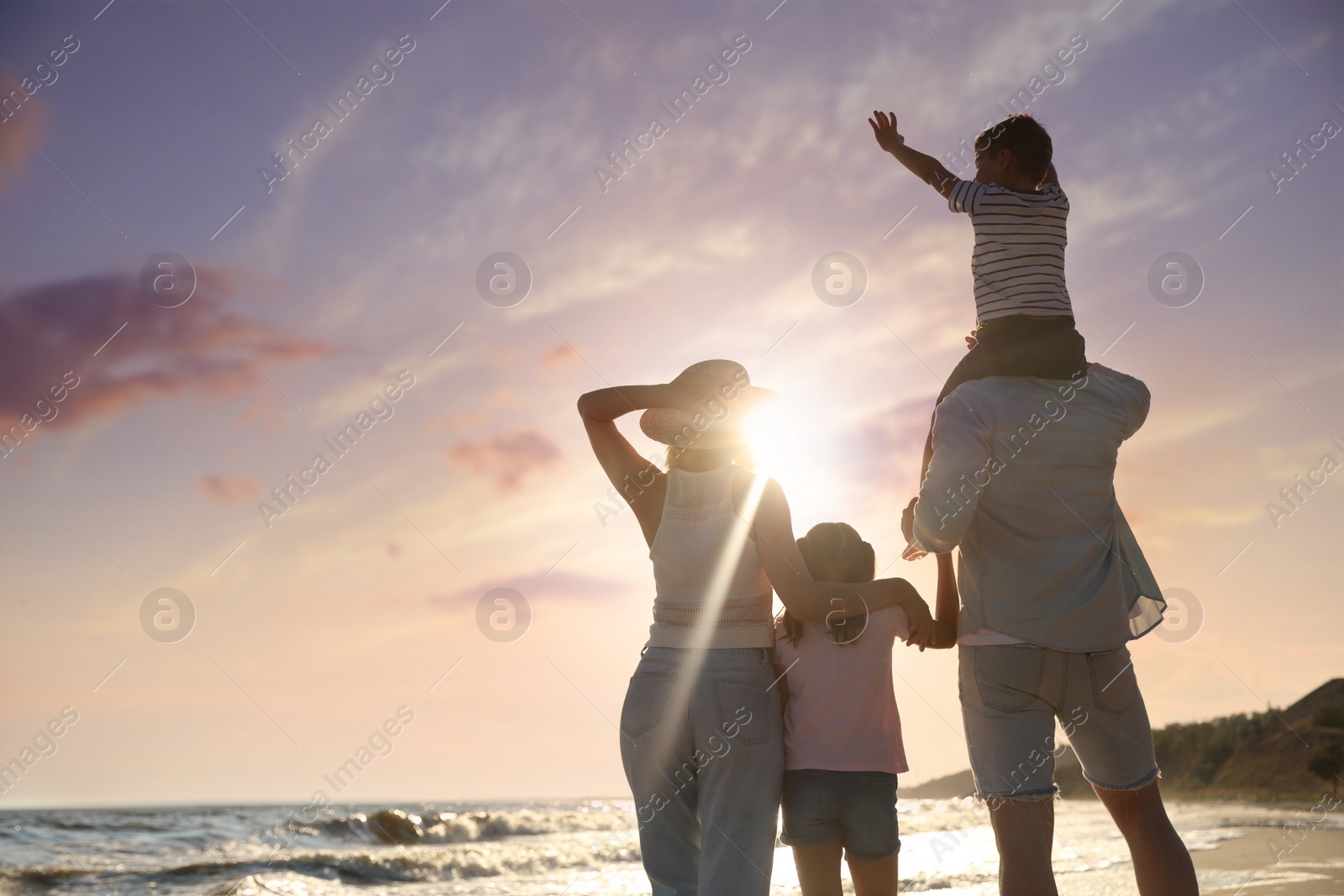 Photo of Family on sandy beach near sea, back view