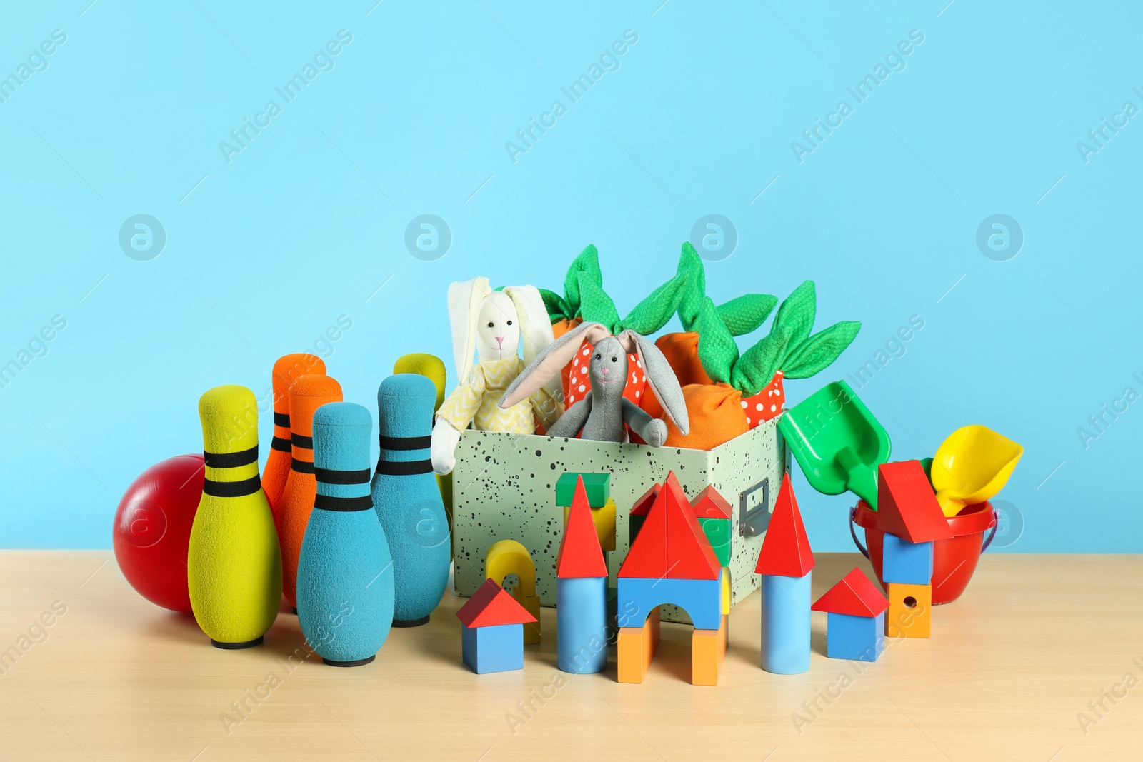 Photo of Many different toys on wooden table against light blue background