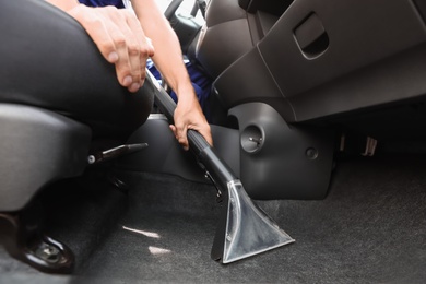 Photo of Man cleaning automobile salon with vacuum cleaner, closeup. Car wash service