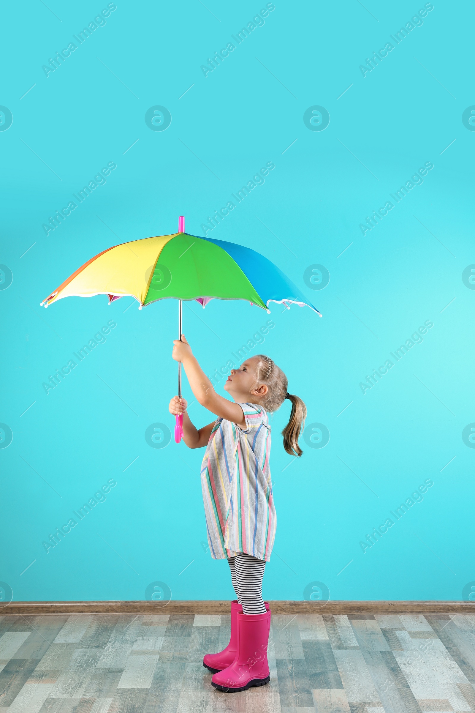 Photo of Little girl with rainbow umbrella near color wall