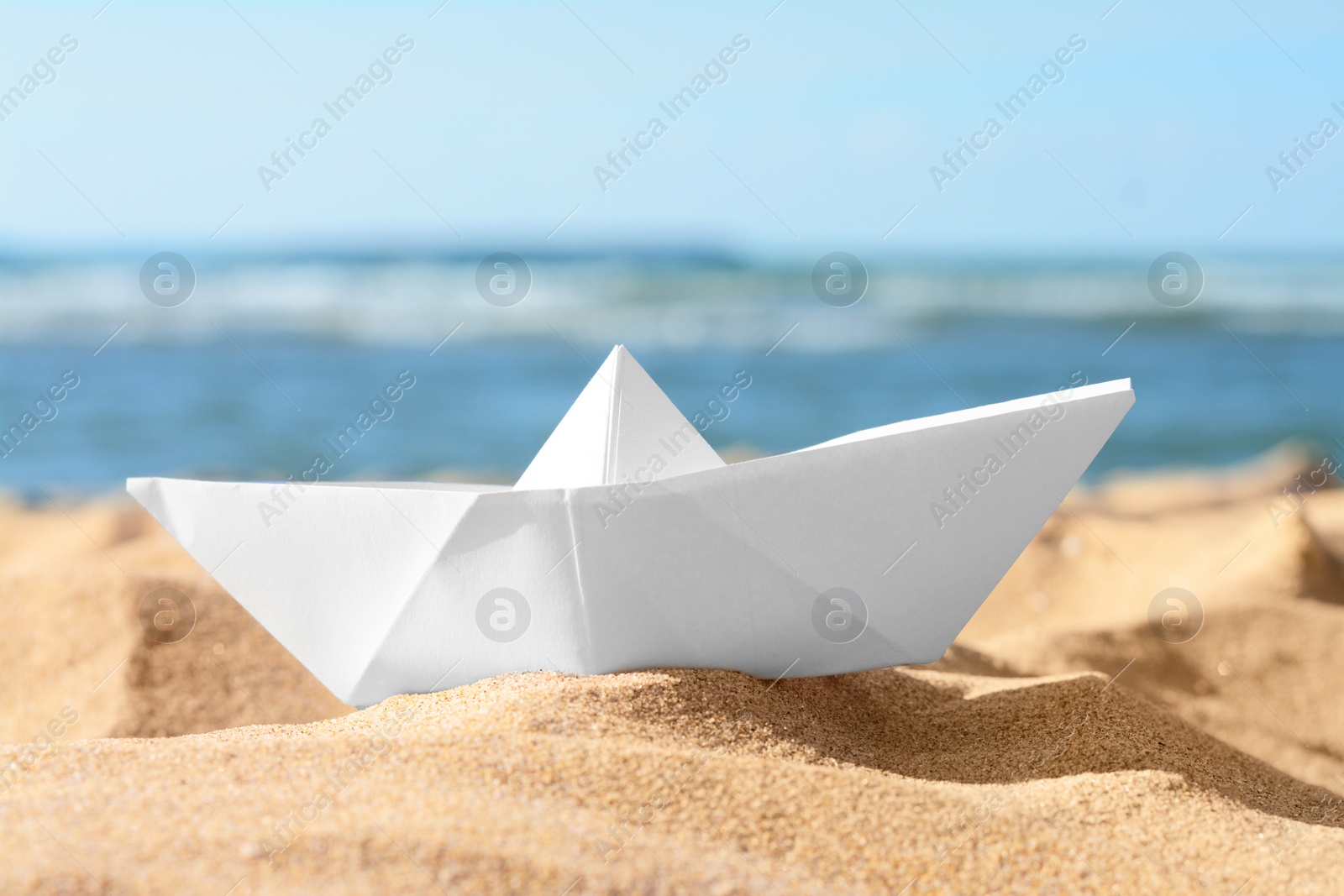 Photo of White paper boat near sea on sunny day, closeup