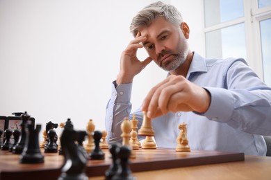 Photo of Man playing chess during tournament at table indoors