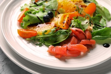 Photo of Delicious salad with salmon on white plate, closeup