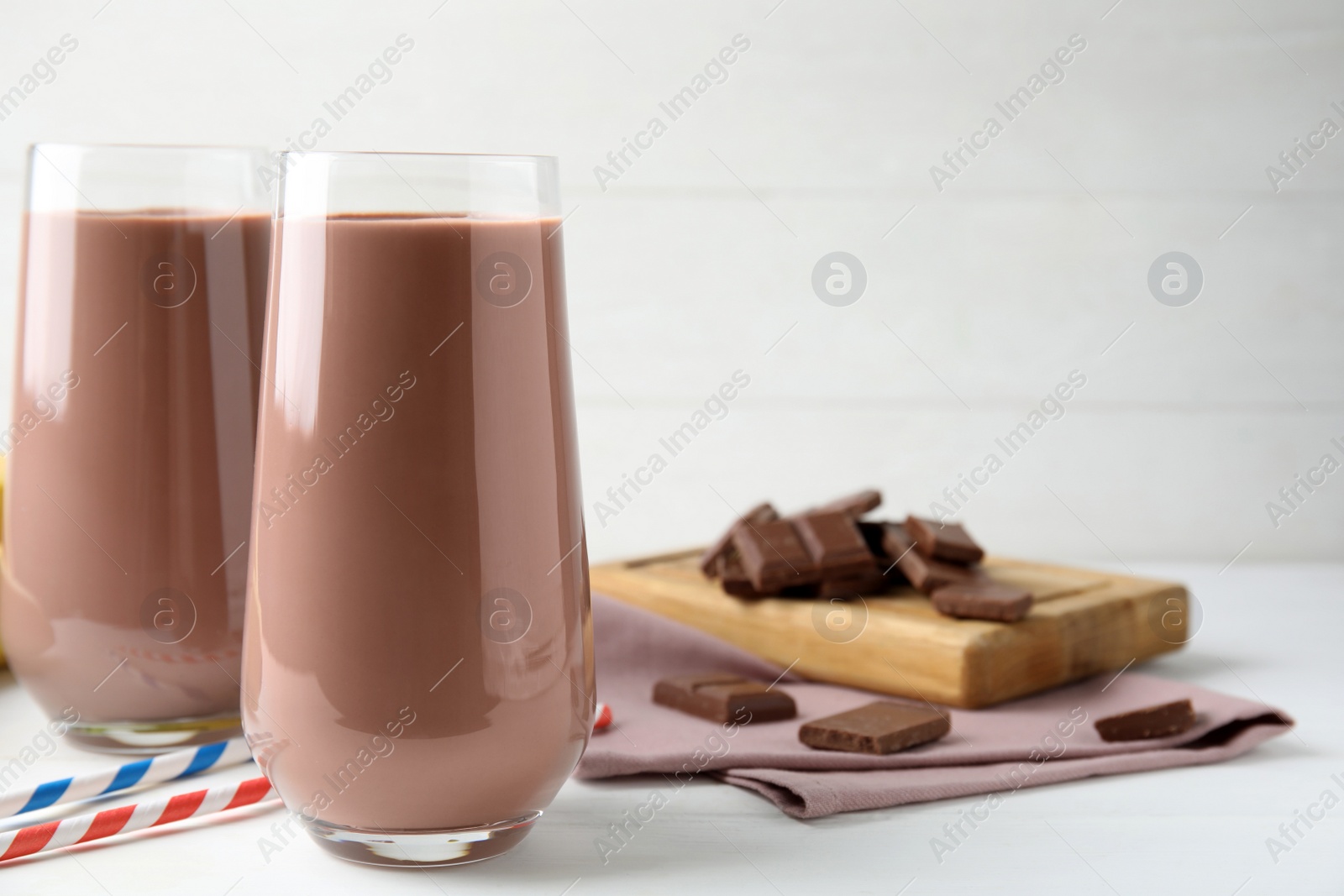 Photo of Fresh yummy chocolate milk on white wooden table. Space for text
