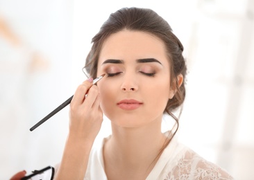 Photo of Professional makeup artist working with young woman in salon