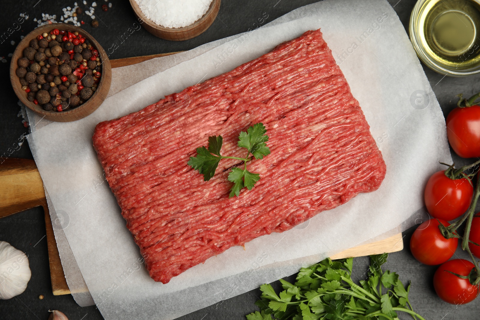 Photo of Raw fresh minced meat, tomatoes and other ingredients on black table, flat lay