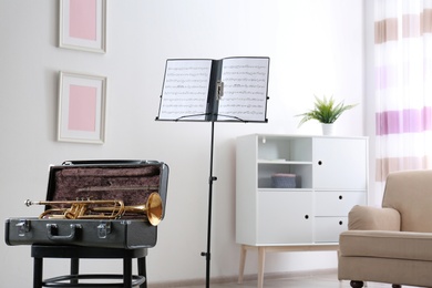 Photo of Trumpet, case and note stand with music sheets in room