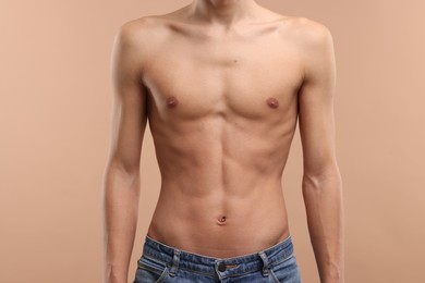 Shirtless man with slim body on beige background, closeup