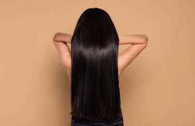 Photo of Woman with strong healthy hair on beige background, back view