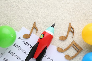 Wooden notes, music sheets and toys on beige textured background, flat lay with space for text. Baby song concept