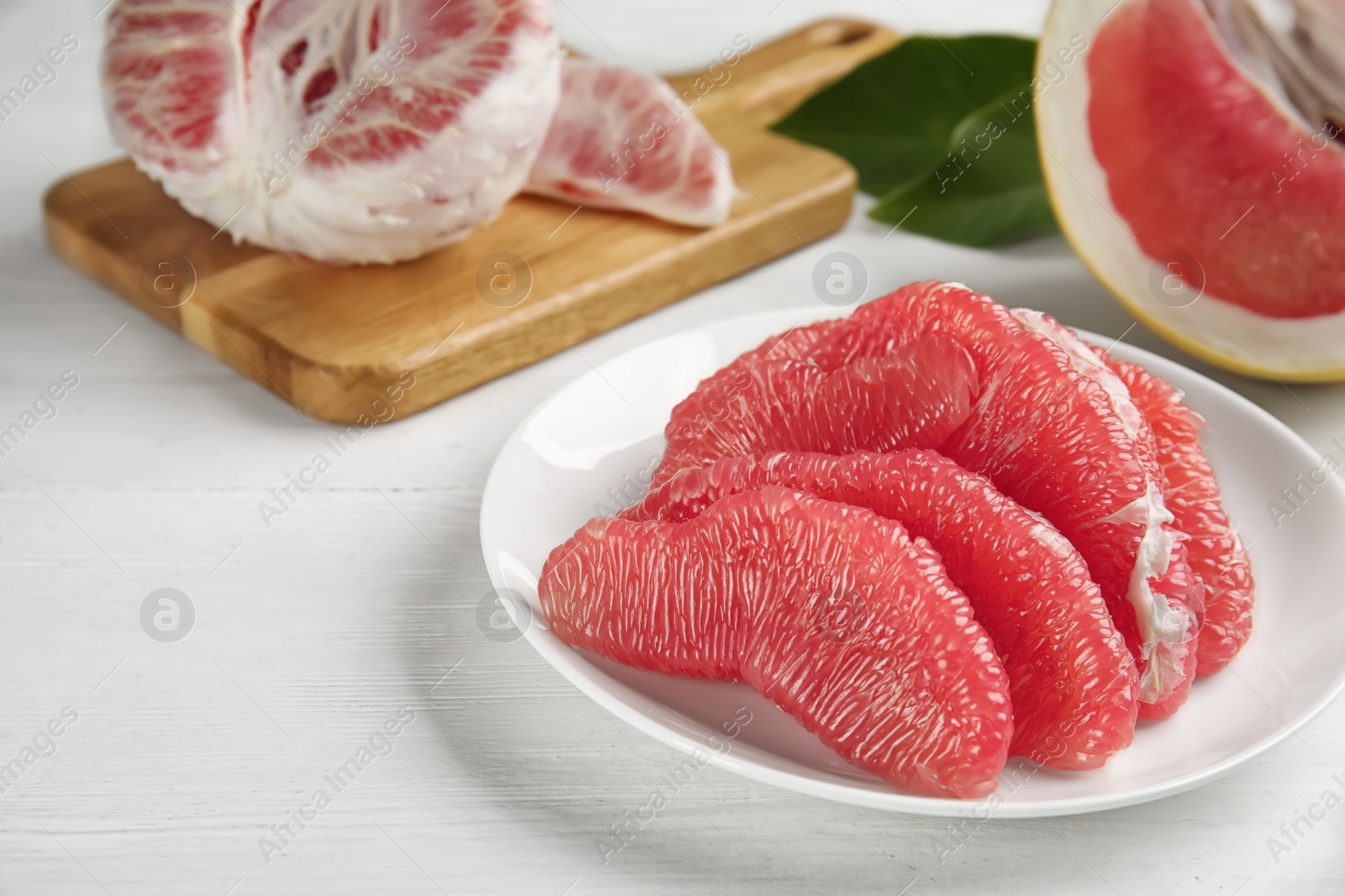 Photo of Peeled red pomelo slices on white wooden table