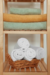Soft folded towels in wicker basket on wooden shelving unit