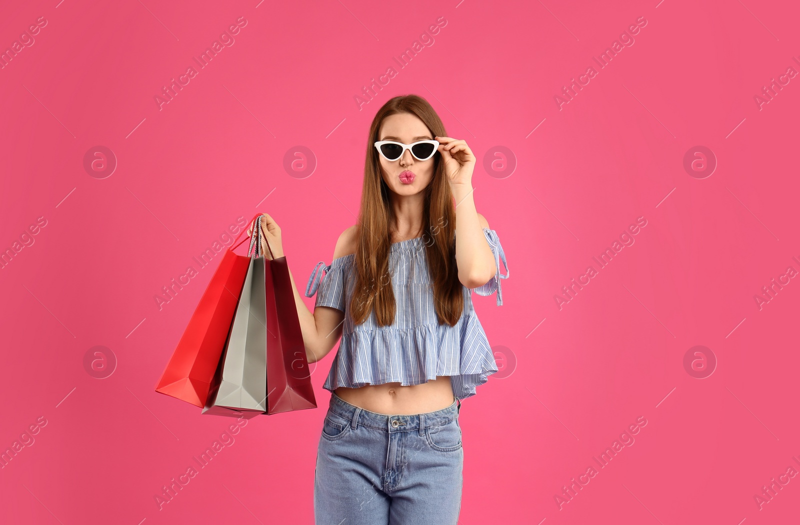 Photo of Beautiful young woman with paper shopping bags on pink background