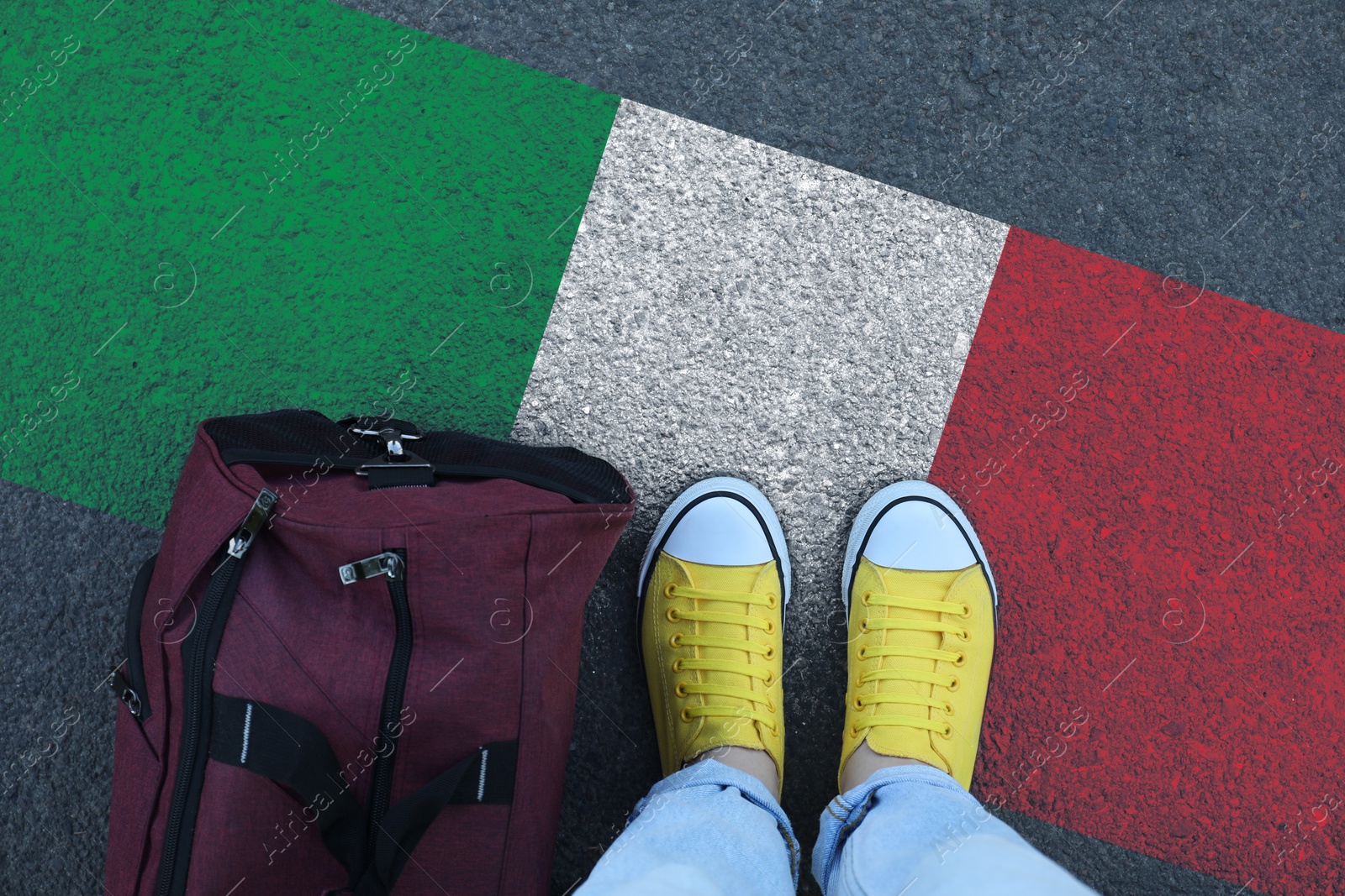 Image of Immigration. Woman with bag standing on asphalt near flag of Italy, top view