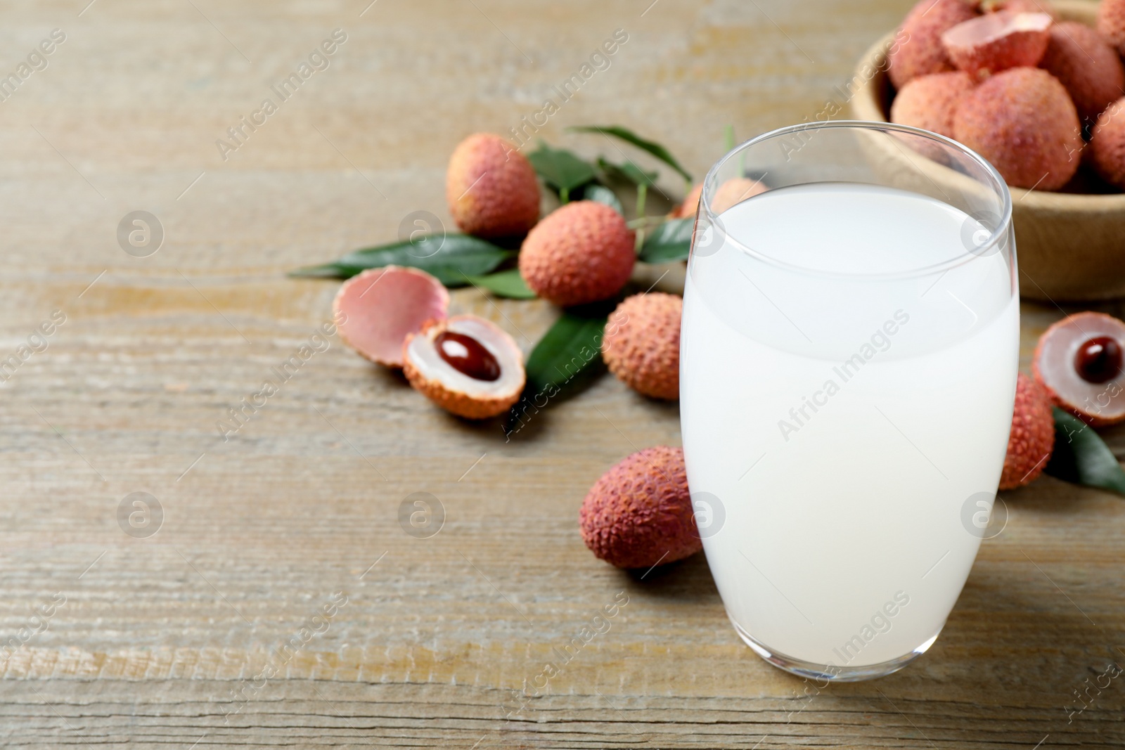 Photo of Lychee juice and fresh fruits on wooden table. Space for text