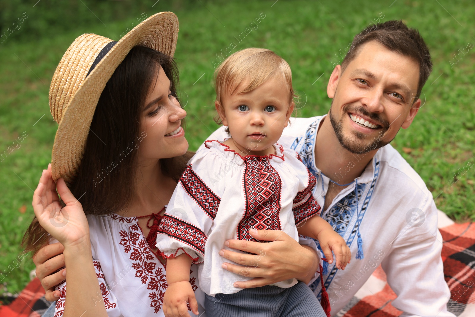 Photo of Happy family in Ukrainian national clothes outdoors