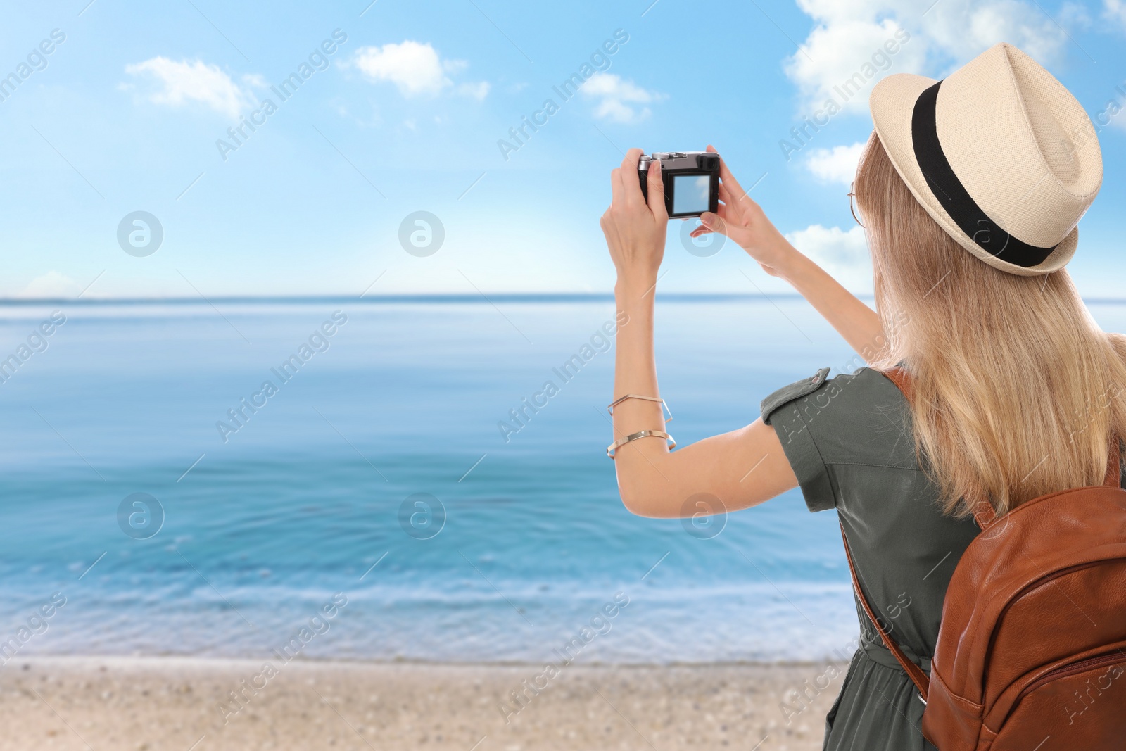 Image of Traveler taking photo on beach during summer vacation trip. Space for text