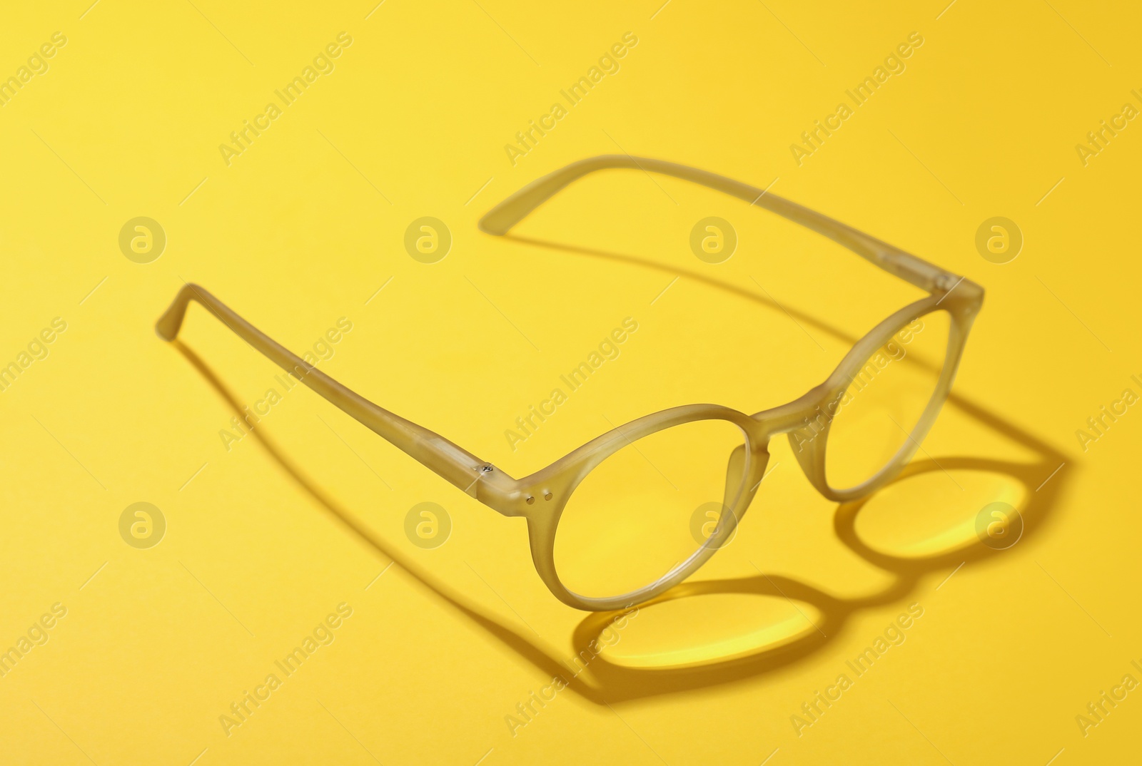 Photo of Glasses with corrective lenses on yellow background