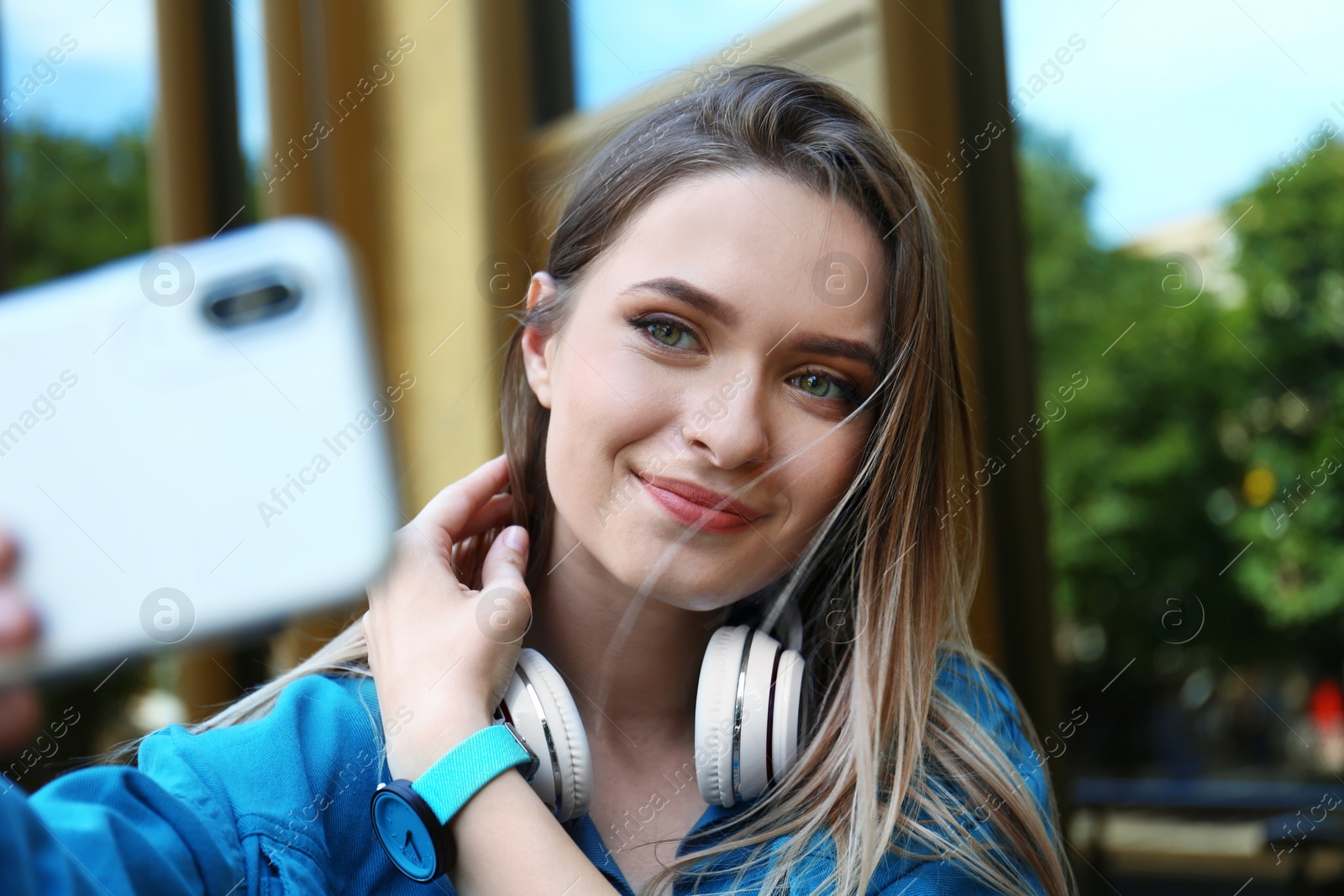 Photo of Happy young woman taking selfie on city street