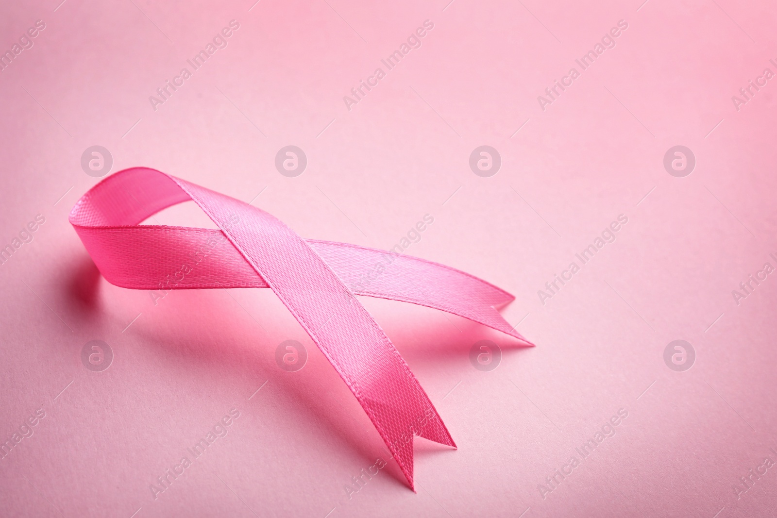 Photo of Pink ribbon on color background, space for text. Breast cancer awareness concept