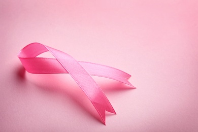 Photo of Pink ribbon on color background, space for text. Breast cancer awareness concept