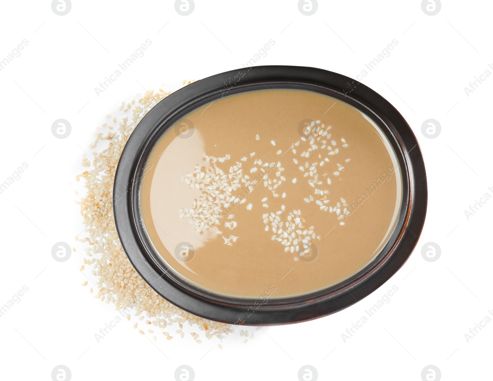 Photo of Tasty sesame paste in bowl and seeds on white background, top view